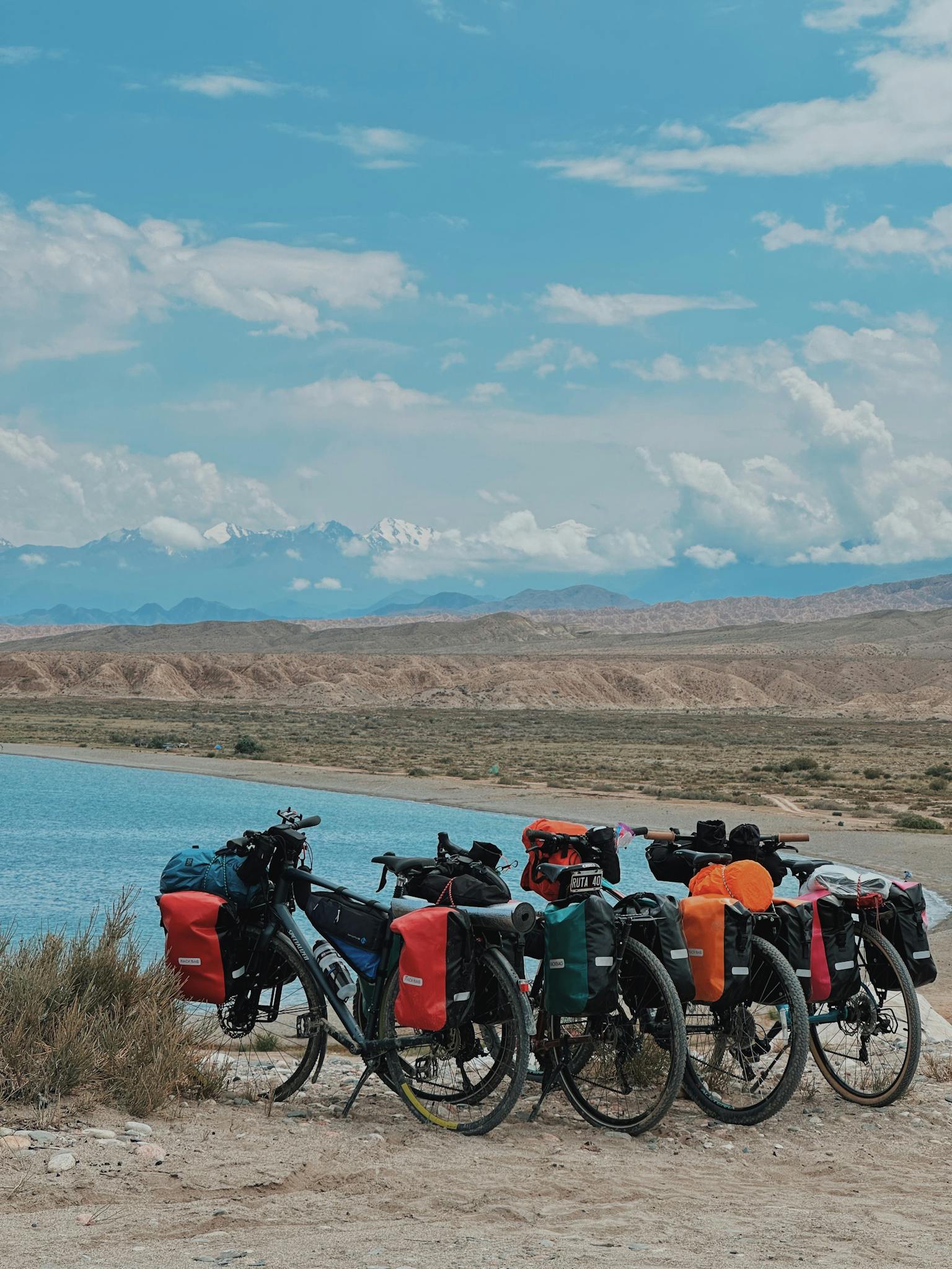 Bicycles parked by a serene lake with a mountain backdrop, perfect for adventure travel enthusiasts.